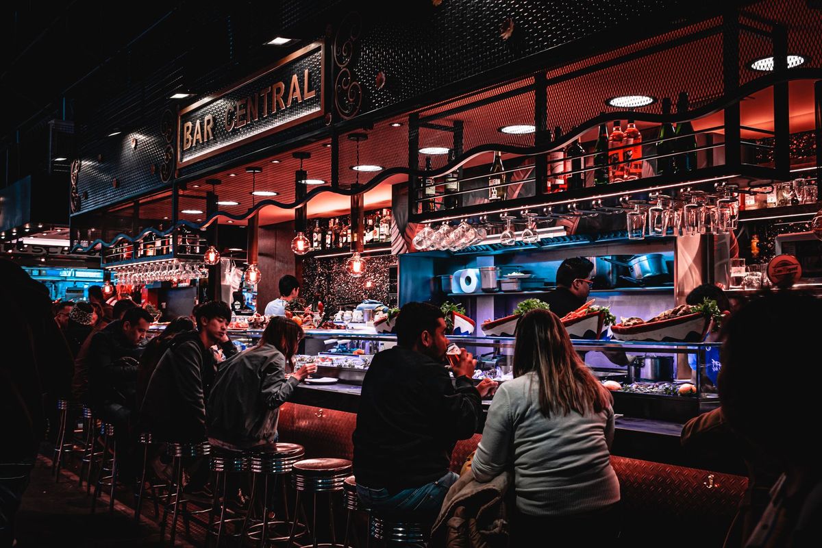 A lively evening scene at Bar Central with adults enjoying drinks and socializing in an ambient restaurant setting.